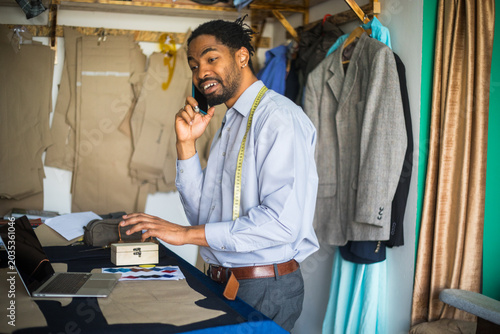 Obraz na płótnie Photo showing african american tailor making business phone call in workshop -st