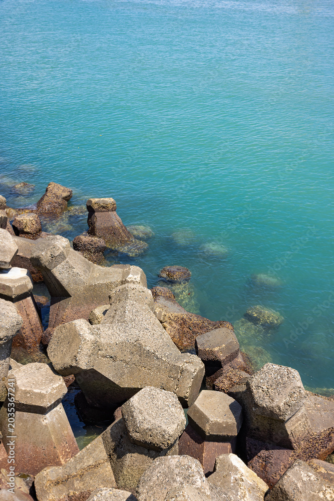 Obraz premium Clear turquoise sea water with concrete breakwater blocks