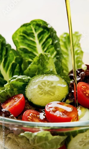 Smooth olive oil pours over fresh salad ingredients with glossy premium healthy food atmosphere
