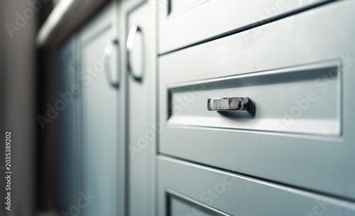 Close up of modern blue kitchen drawer and cabinet details with soft natural light and shallow depth of field.