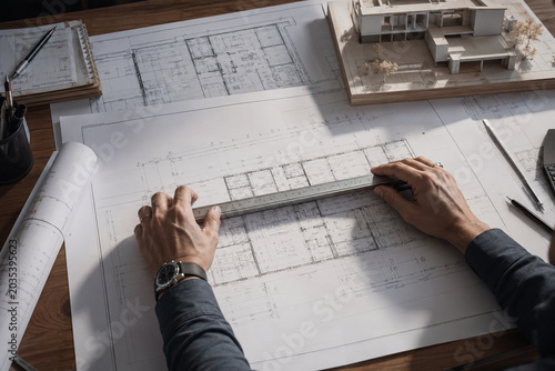 Architect hands working on a detailed blueprint and scale model