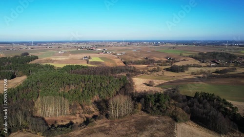 Backward drone flight over patchwork farmland and woodland groves