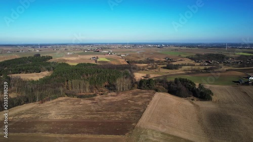 Backward drone flight over patchwork farmland and woodland groves