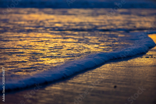 Golden sunset waves washing onto a tranquil beach shoreline, ideal for travel ads, wellness blogs, meditation backgrounds, tourism campaigns, website banners, wallpapers, and social media.