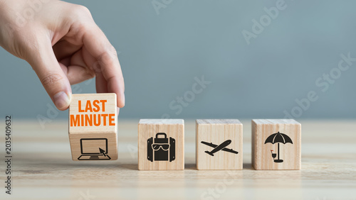 Last Minute Travel Concept – Hand Lifting Wooden Block with Icons for Spontaneous Booking, Travel Agency Websites, and Holiday Planning