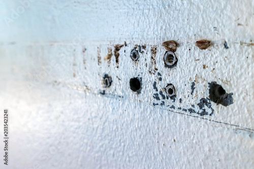 Close up of plastic wall plugs inside drilled holes on dirty concrete wall. Plastic dowels or wall anchors embedded into holes drilled in an old concrete wall. Home renovation and repair concept.