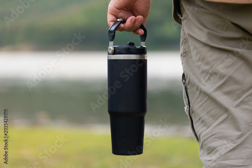 Quadro su tela Close up of a traveler hand holding a black stainless steel tumbler by the handl