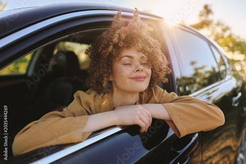 Obraz na plátne Young woman enjoys a calm drive, leaning on the car window with a soft smile, wa