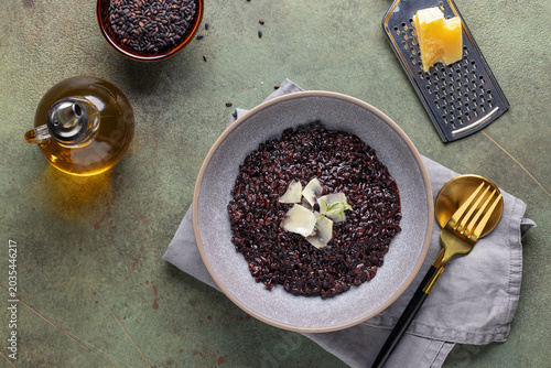 Black rice risotto with cheese and thyme in ceramic plate. Italian Cuisine. Top view