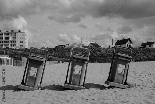 Bilde på lerret Trash bins on a sandy beach near coastal houses