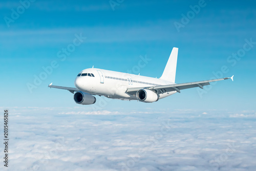 Photos White passenger jetliner flies in the air above the clouds