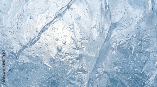 An abstract winter pattern of blue ice texture and frosty crystal formations on a cold glass window surface