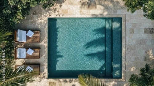 Aerial view of serene outdoor pool with sunbeds and lush greenery