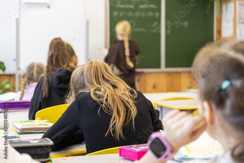Obraz na plátně Elementary school students sit at desks in a classroom, focusing on their studie