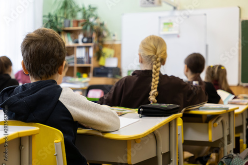 Students sitting at desks in an elementary school classroom, focused on a lesson while learning together in a bright, modern academic environment to foster personal development