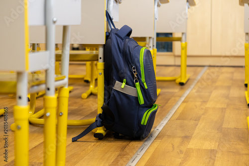 Blue school backpack hanging on a chair in a modern classroom, representing academic life, primary school education, and preparation for students in an elementary learning setting