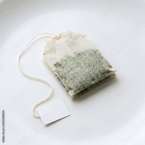 Simple green tea bag with a blank label, poised on a clean white surface, promising a refreshing and natural infusion