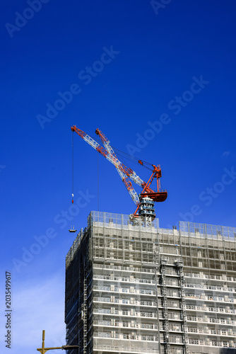 construction tower crane work with construction worker on top of building, used in construction site with blue sky.
