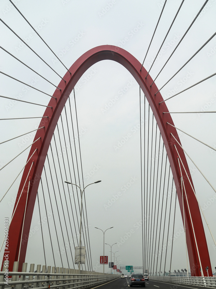 Fototapeta premium Red Cable-Stayed Bridge with Symmetrical Arch Design