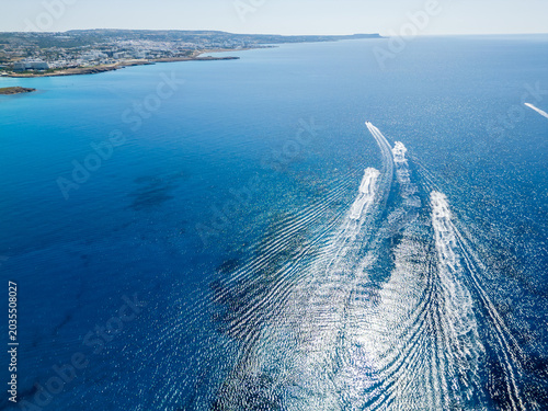 Aerial View of Speedboats and Wakes Crossing Clear Turquoise Ocean Water on a Sunny Day