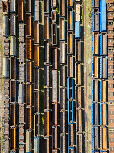 Many railroad cars (rail cars) of different cargo types on multiple parallel railway tracks, seen from above the railway station