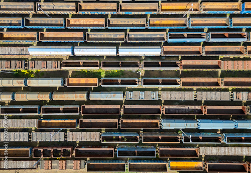 Many railroad cars (rail cars) of different cargo types on multiple parallel railway tracks, seen from above the railway station
