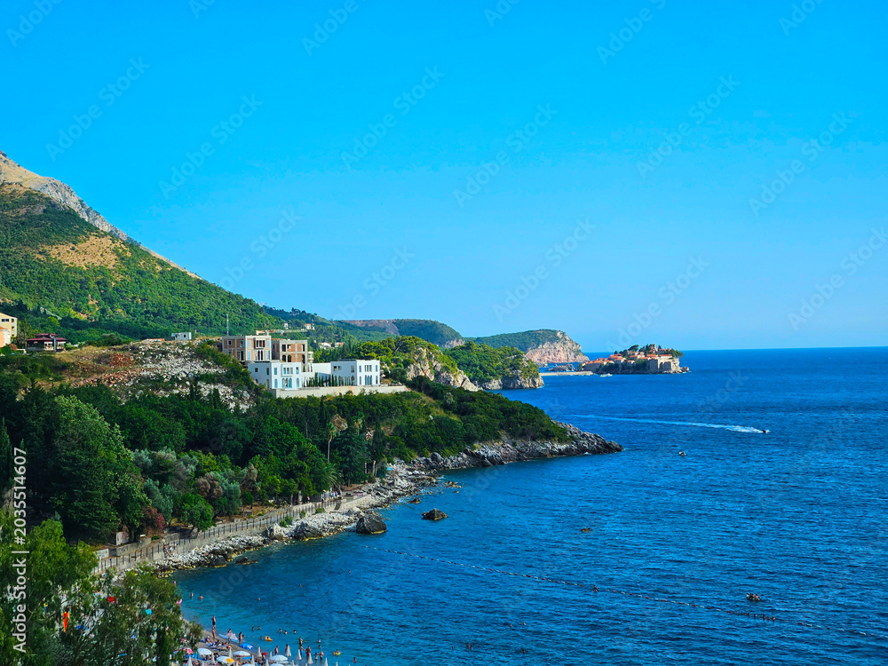 Fototapeta premium landscape sunny day, hills and rocks of Montenegro, city of Budva, white houses visible on the hills. Clear blue sky and bright blue Adriatic sea,