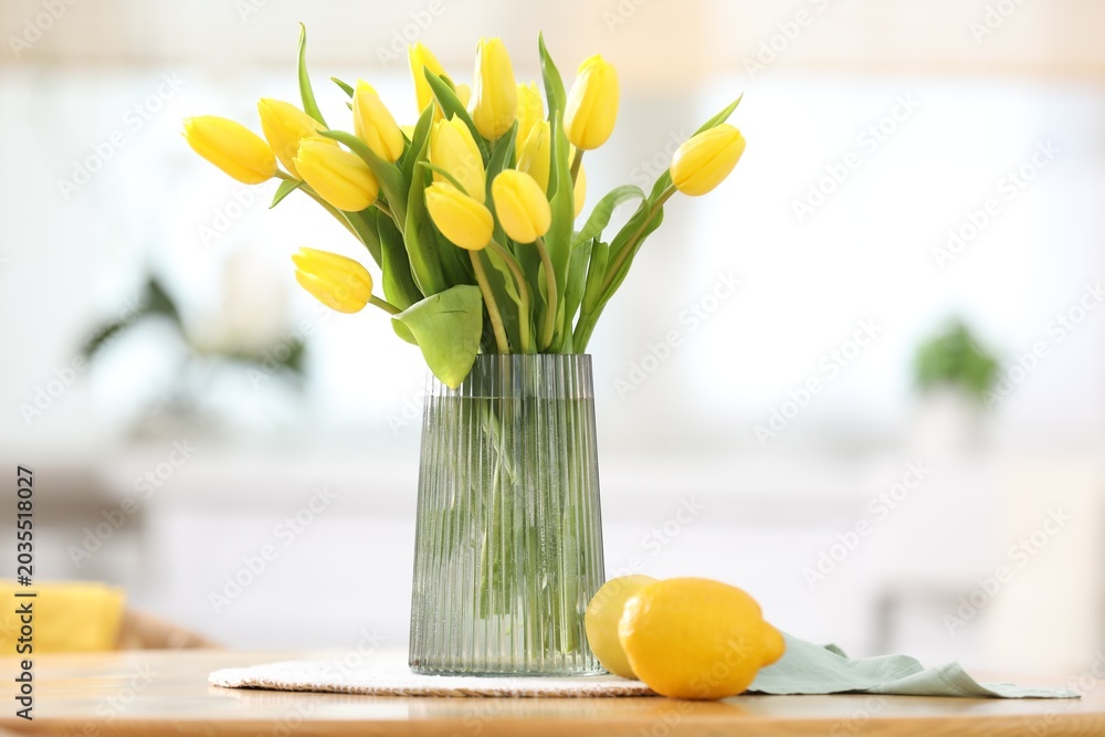 Fototapeta premium Beautiful tulips in vase on wooden table in kitchen