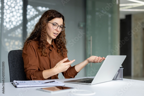 Canvas Print Young businesswoman with glasses conducting a professional video call on a lapto