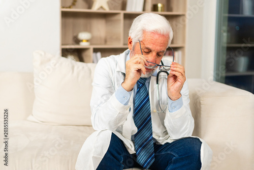 Photos Sad tired mature senior male doctor in medical uniform in hospital or doctor office