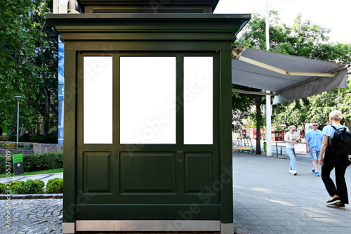 blank white billboard, ad sign. digital lightbox. outdoor poster panel for mockup. empty placeholder. urban setting. painted green wood paneling. glass and wood frame. streetscape