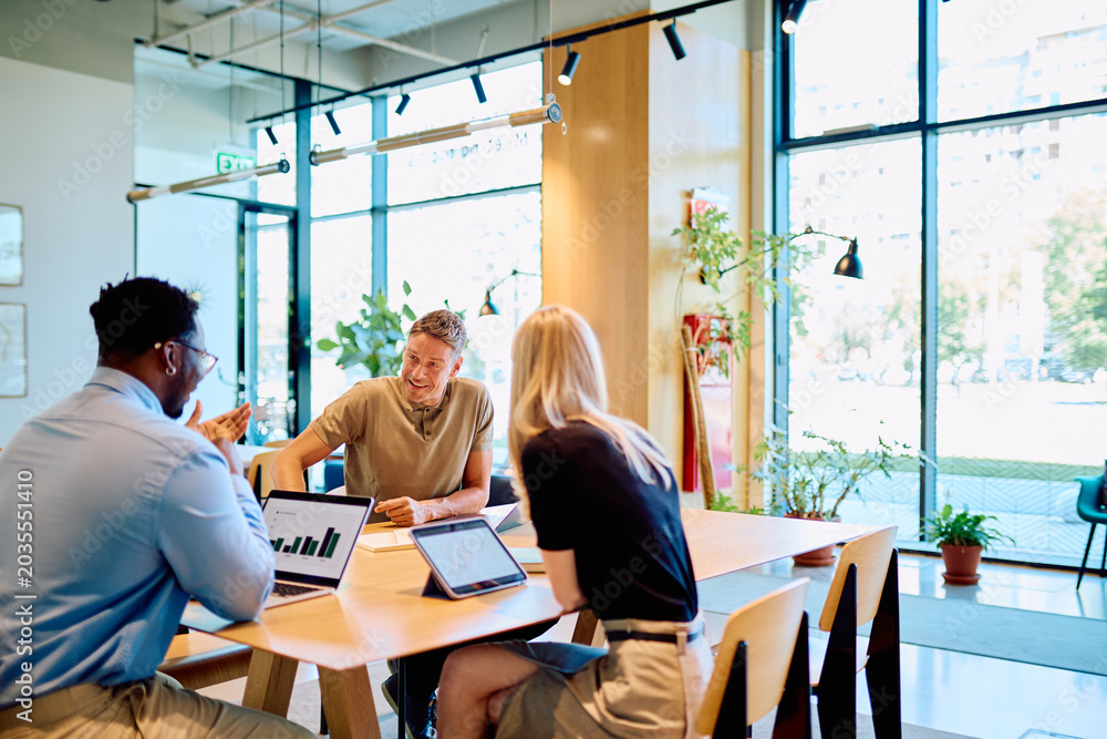 Obraz premium Diverse business professionals collaborating on a startup project, analyzing data on laptop and tablet during an office meeting