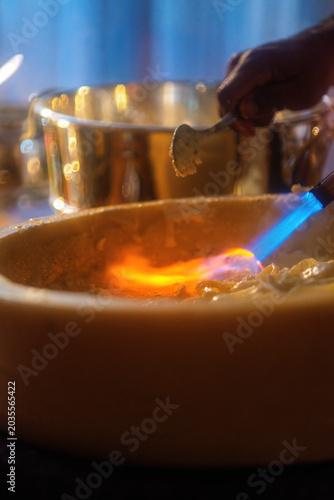 Pasta preparation with chef using torch at restaurant during evening service