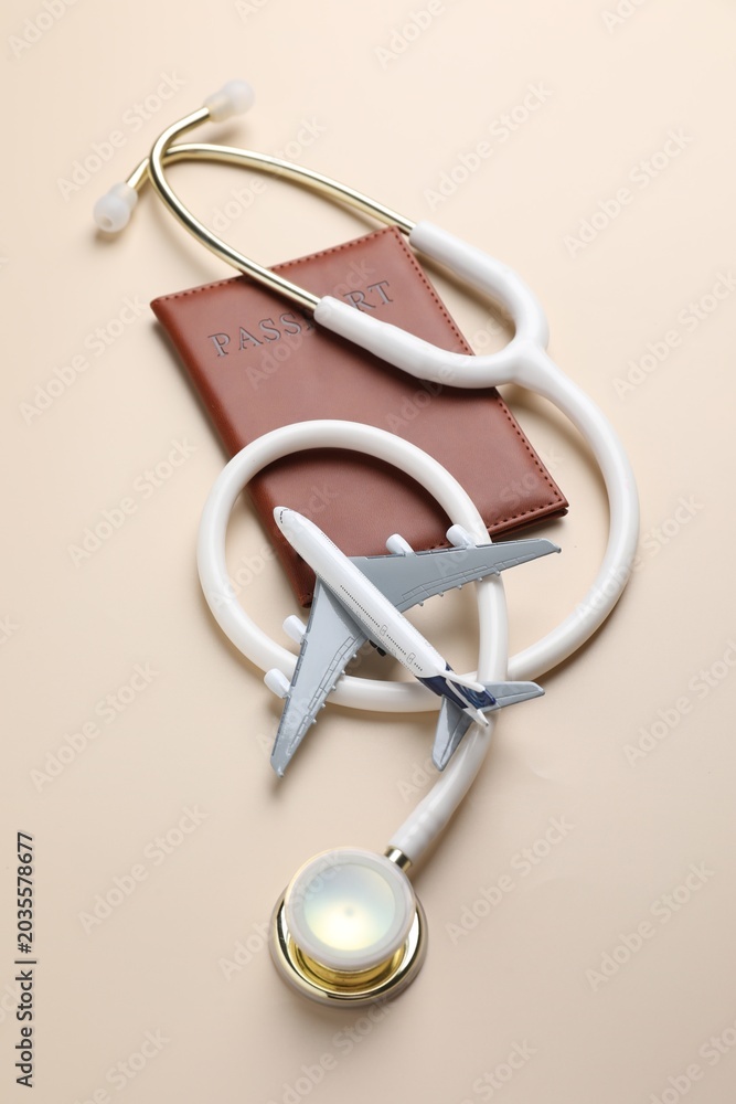 Obraz premium Medical tourism. Passport, stethoscope and plane model on beige background, flat lay