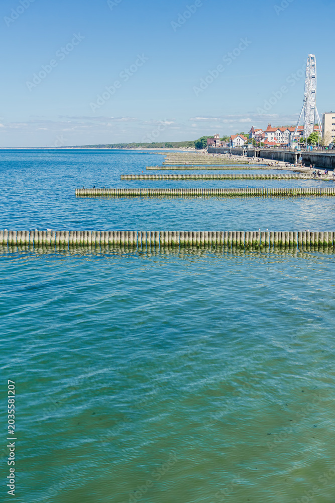 Obraz premium Turquoise Sea with Wooden Breakwaters Coastal Town