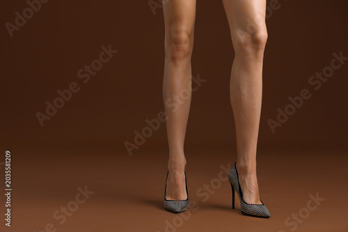 Obraz na plátne Woman wearing stylish high heeled shoes on brown background, closeup