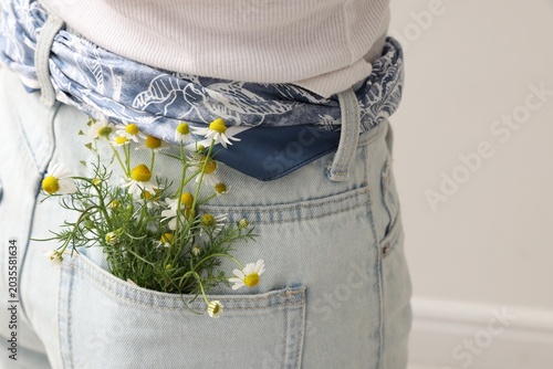 Woman with flowers in her pocket on light grey background, closeup