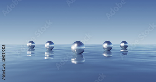 Fotografie Conjunto minimalista de esferas metálicas que se reflejan en aguas azules cristalinas con un cielo infinito