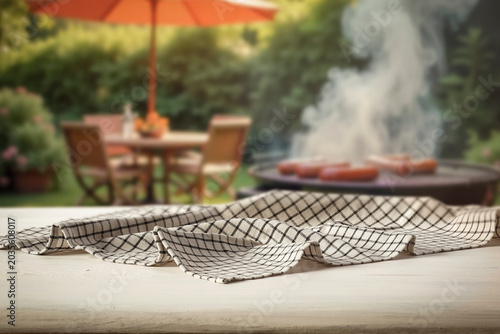 Wooden table with clean copy space for product placement and relaxing summer atmosphere with blurred summer picnic background.