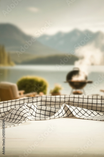 Wooden table with clean copy space for product placement and relaxing summer atmosphere with blurred summer picnic background.
