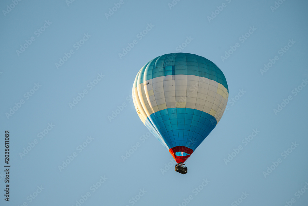 Obraz premium Blue and white hot air balloon floating against clear sky.