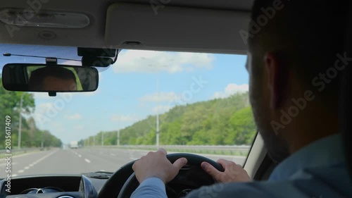 Young man looking straight while driving a car while concentrating on the road. Right hand drive car. Lifestyle, travel concept. Real time