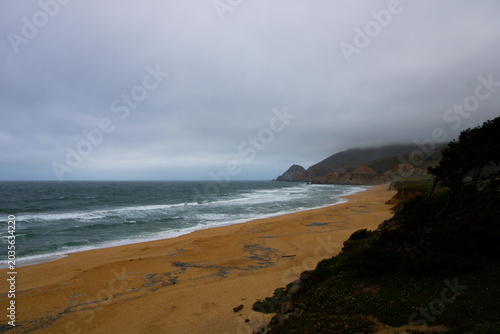 Canvas Print Wide beach panorama with wet sand stretching toward a distant rocky headland