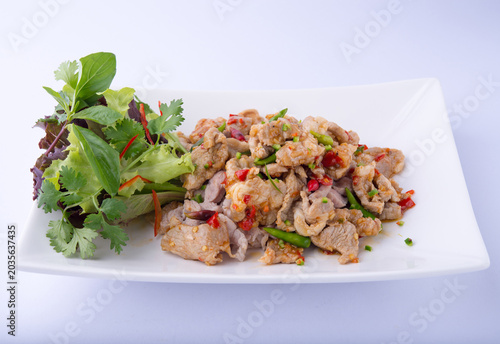 Quadro em tela Stir-fried Pork with Chili: Garlic, fresh chili seeds, and chopped fresh chilies stir-fried and coated in a brown sauce, with basil leaves, served in a white dish against a white backdrop