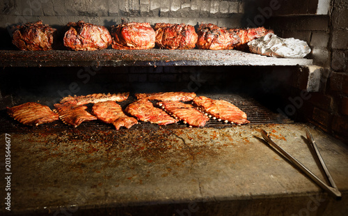 BBQ pork ribs and shoulder being smoked on a grill at a barbeque restaurant.