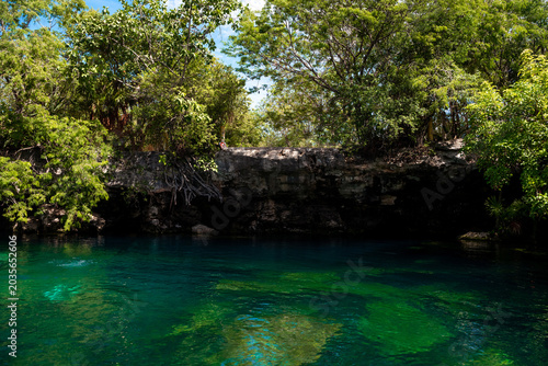 Cenote with turquoise water and rocky cliff