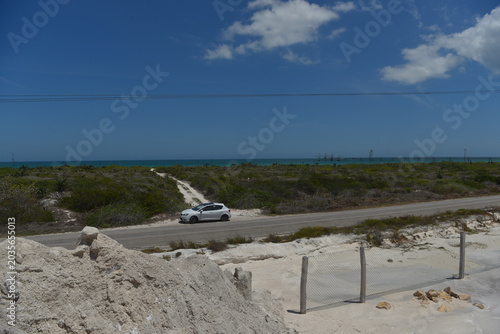 White car on coastal road near turquoise ocean