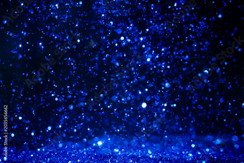 Drops of water create blue sparkles in the dark setting during nighttime