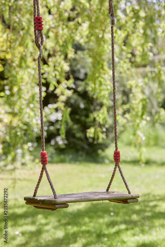 wooden swing seat on a rope in a garden or park