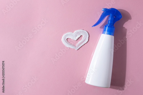 Bottle of sunscreen and texture of cream on colored background top view